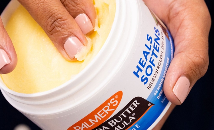 Palmer's Cocoa Butter for Sunburn being scooped out of jar by woman's hand